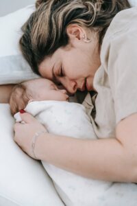 niemowlę w śpiworku śpiące obok mamy